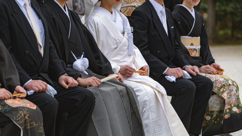 黒留袖、白無垢を着た女性と羽二重黒紋付を着た男性と洋装の男性が並んで座る様子