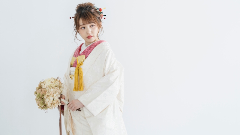 手に花束を持ち、白無垢に色掛下を合わせた衣装の花嫁