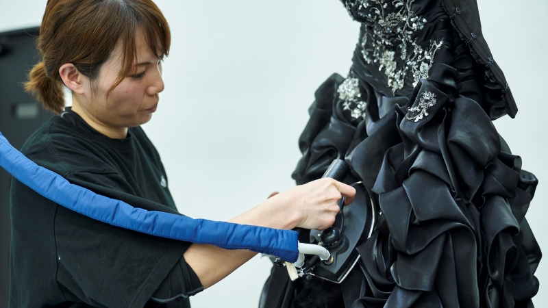 衣装をプレスするディアハートのクリーニングスタッフ