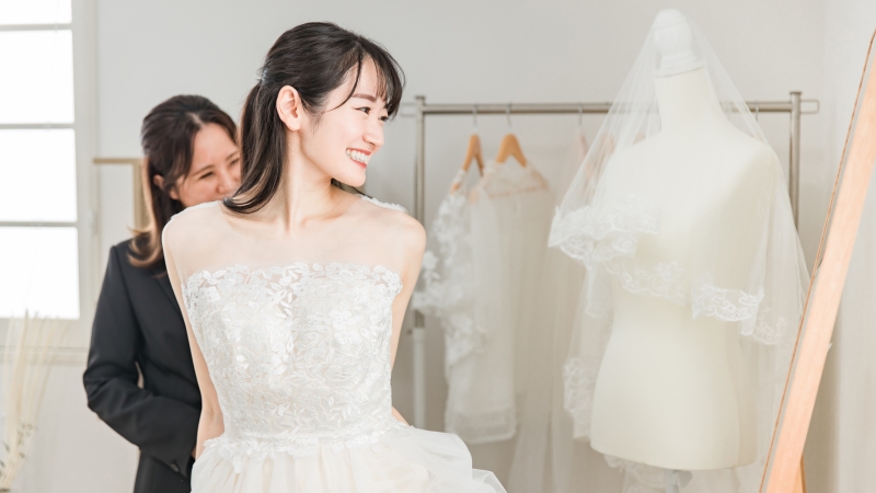 スタイリストさんと一緒にウエディングドレスをしちゃくする女性
