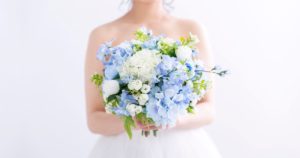 水色と白を基調としたブーケを持つウエディングドレス姿の花嫁