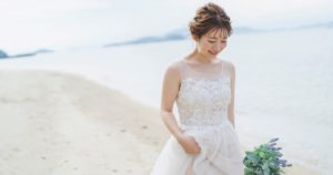 ウエディングドレス姿で海水近くの海辺を歩く花嫁